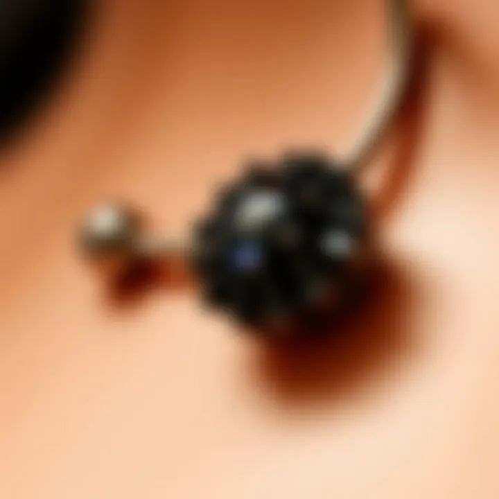 Close-up of a belly button ring adorned with dark gemstones